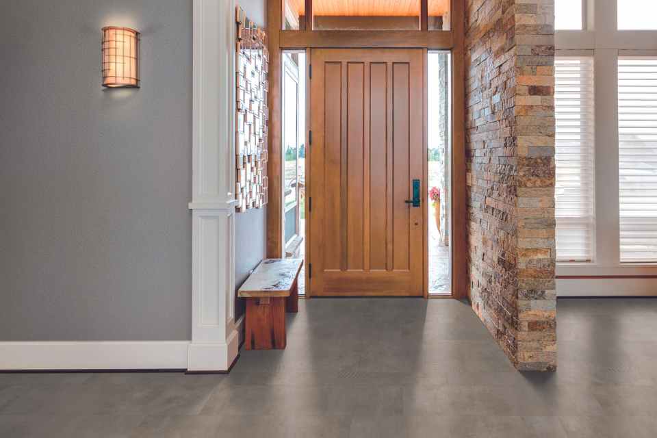 classic concrete look luxury vinyl tile in entryway with brick wall
